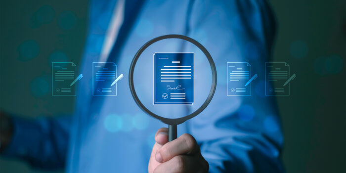 Professional examining regulatory compliance documents through a magnifying glass with digital document icons in the background